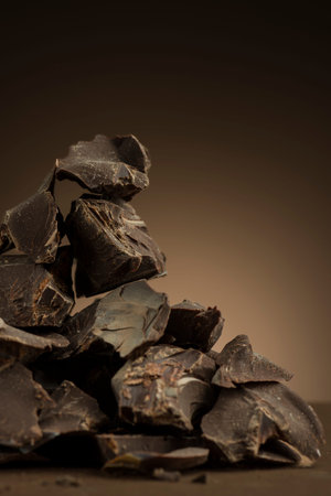 Pile of dark chocolate flakes on brown background.