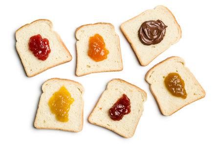 Slices of white bread with variety of jam on white background, top view.の写真素材