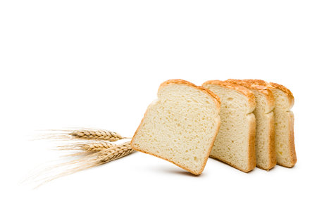 Slices of white bread with ears of wheat on white background.の写真素材