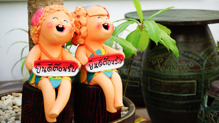 Twins ceramic figures hold boards say "welcome" in Thai language which placed in front of the resort.の写真素材