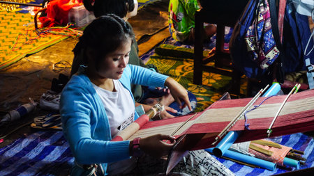 Kanchanaburi, Thailand - December 31, 2016: Mon woman is weaving a fabric at Sangkhlaburi street market, Thailand in the night time of December 2016のeditorial素材