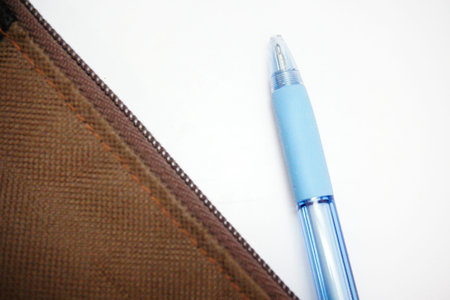 A blue pen is taken out of a brown pencil-bag on a white background, close-up shot.