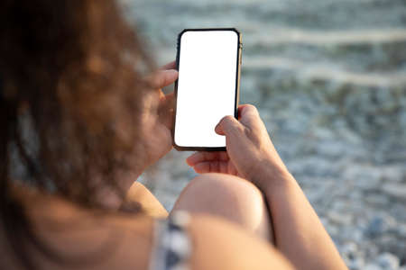 woman on vacation by the sea with a smartphone in handの写真素材
