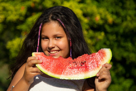 gipsy girl with long black hair eats the big slice of watermelonの写真素材
