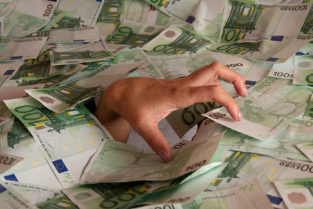 Concept of being hungry for money. Money at any cost, hand immersed in moneyの写真素材