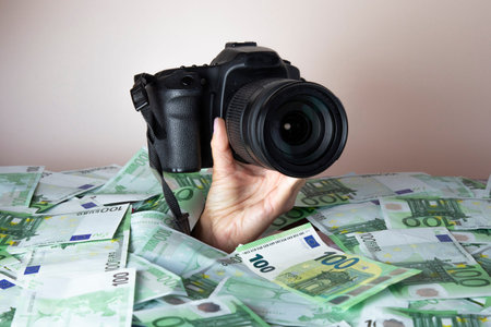 Concept make good money on photography .hand with a camera crawls out of a pile of money