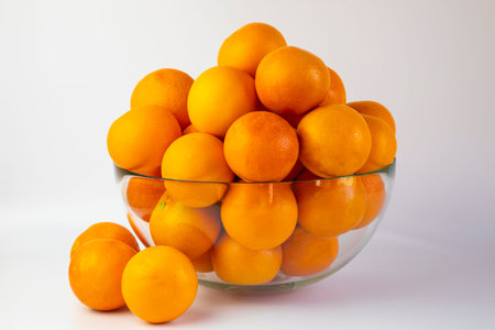 oranges in a large transparent bowl on a white background