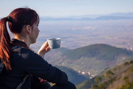 Tracker woman on top of the mountain drinks a hot drinkの写真素材