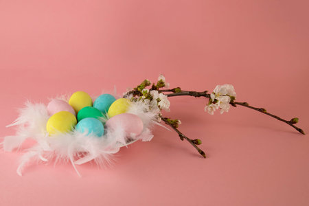 Happy Easter! Easter card with a picture of a nest of colored eggs on a pink background decorated...