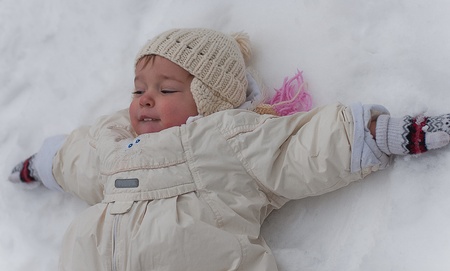 Little girl lays on snowの写真素材