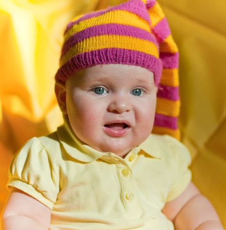 Surprised baby in the yellow and pink hatの写真素材