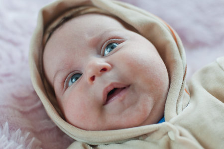 Thoughtful Baby in hood laying and looking up