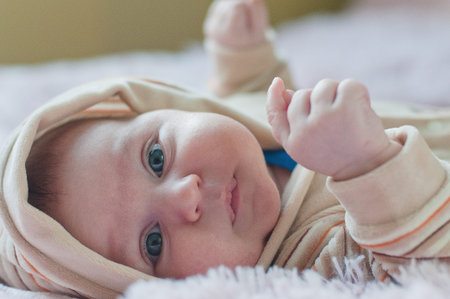Thoughtful Baby in hood laying and looking forward