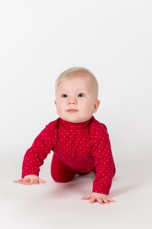 Crawling baby in red suite on the white backgroundの写真素材