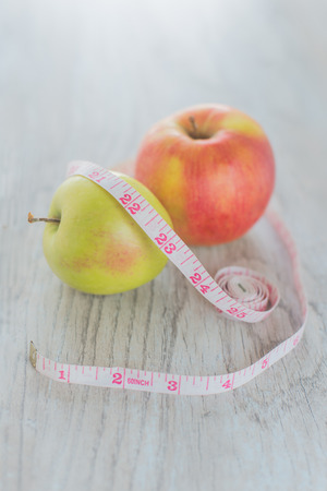 Apples in the measuring tape on the wood backgroundの写真素材