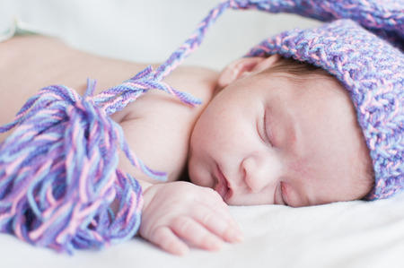 Horizontal portrait of the sleeping baby in purple hatの写真素材