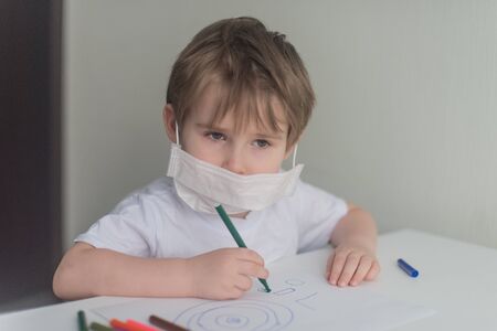 Little boy sits near the table and drawingの写真素材