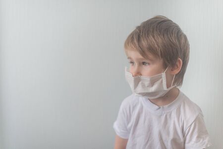 Little boy in medial mask looks left thoughtfullyの写真素材