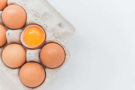Close up of the Package of ten brown eggs and one broken egg on the whiteの写真素材