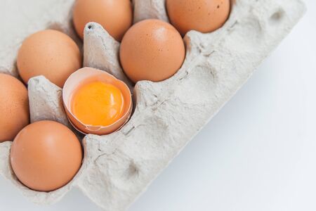 Close up of the Package of ten brown eggs and one broken egg on the whiteの写真素材