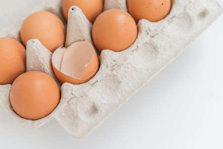 Close up of the Package of ten brown eggs and one broken egg on the whiteの写真素材