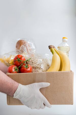 Man in rubber gloves holds the box with food. Donation food deliveryの写真素材