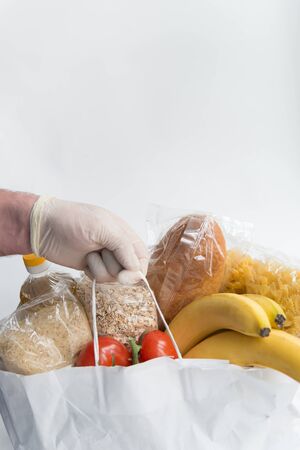 Man in rubber gloves holds the paper bag  with food. Donation food deliveryの写真素材