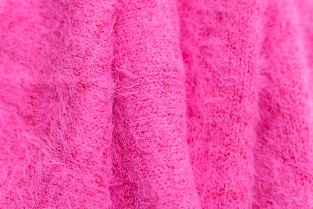 Pattern of pink knitted sweater  closeup. Handmade merino wool product. A stack of folded clothesの写真素材