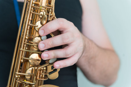 Hand of man playing on saxophone. Musician in black shirt plays saxの写真素材