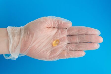 Doctor hand in medical glove holds gold fish oil capsule. Vitamin D deficite preventionの写真素材