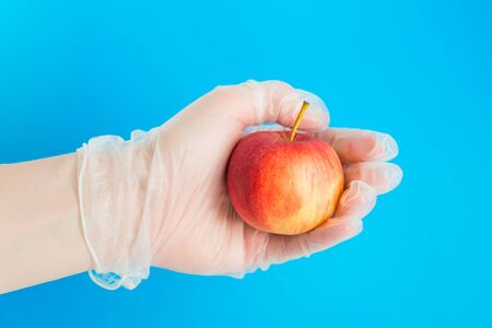 hand in rubber glove holds the red apple. Conception of safe deliveryの写真素材