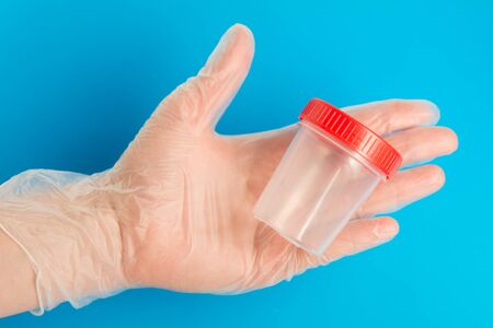 Doctor hand in medical glove holds an empty plastic container for testsの写真素材