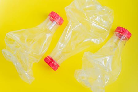 Three crushed plastic bottles flat lay on the yellow background. No waste and recycle conceptの写真素材