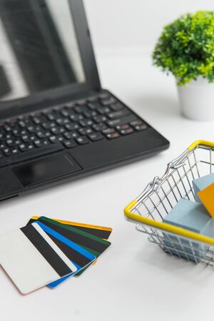 Laptop, green plant, shopping basket and credit cards. Online shopping and delivery conceptionの写真素材