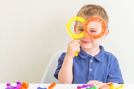 Adorable boy made glasses of plastic block toy and smiling.Copy space. Horizontal photo of funny toddlerの写真素材
