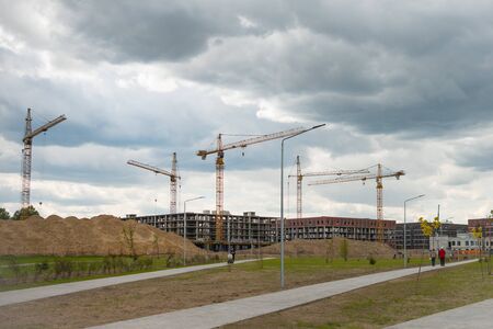 Construction cranes near the unfinished buildings. Construction and developing new districts conceptの写真素材
