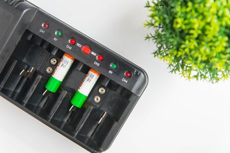Flatlay of recharging batteries and green plant on the white. Ecology safety and energy efficient concept with copy spaceの写真素材