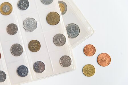 Top view of the numismatic album sheets and coins. Collection of rare coins on the white background with copy spaceの写真素材