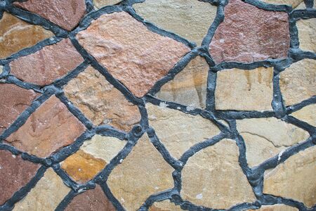 Natural colored stone block paving texture. Stone wall with black seams. Building backgroundの写真素材