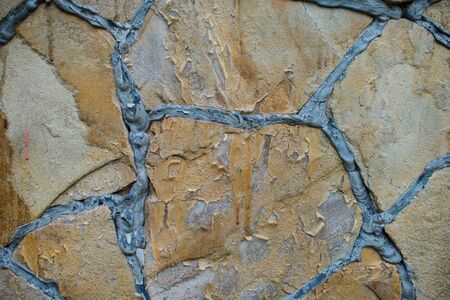 Natural brown stone block paving texture. Stone wall with black seams. Building backgroundの写真素材