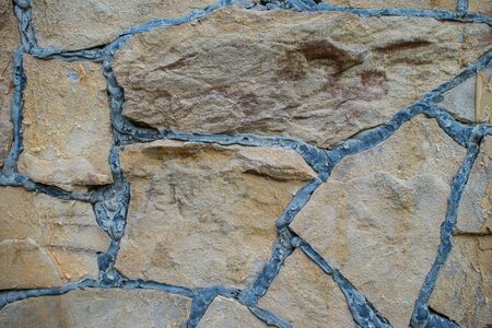 Natural brown stone block paving texture. Stone wall with black seams. Building backgroundの写真素材