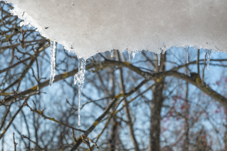 Melting icicles on the roof in gardenの写真素材