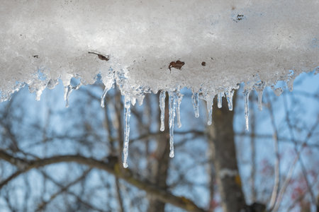 Melting icicles on the roof in gardenの写真素材