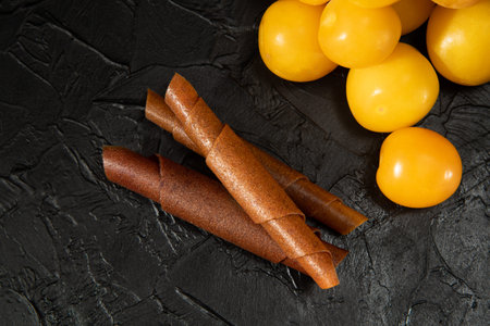 Pastila fruit skin rolls with fruits on a black background. Vegetarian food. Sweet without sugar.