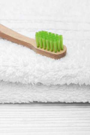 Ecological wooden toothbrush with green bristles on a white towel. Oral hygiene.の写真素材