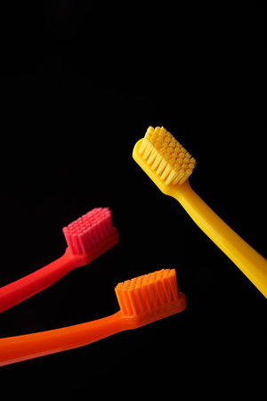 Three colored plastic toothbrushes on a black background. Oral hygiene of the mouth. Dentist.の写真素材