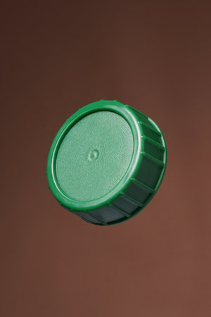 Green plastic bottle cap on a brown background. Close up.の写真素材