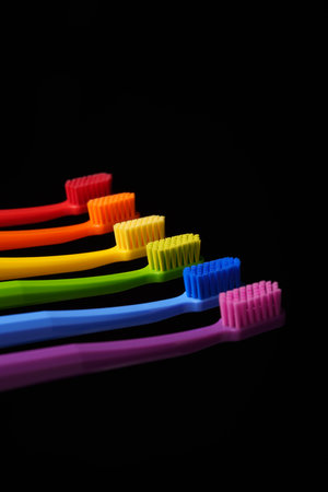 Multicolored plastic toothbrushes on a black background. Colors of the rainbow.の写真素材