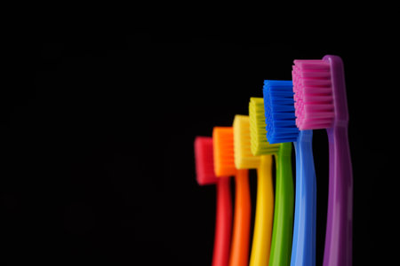 Multicolored plastic toothbrushes on a black background. Rainbow colors.の写真素材