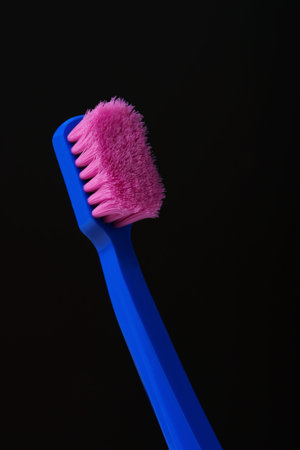 Used plastic toothbrush with pink bristles on black background. Time to throw it away and replace it with a new one.の写真素材